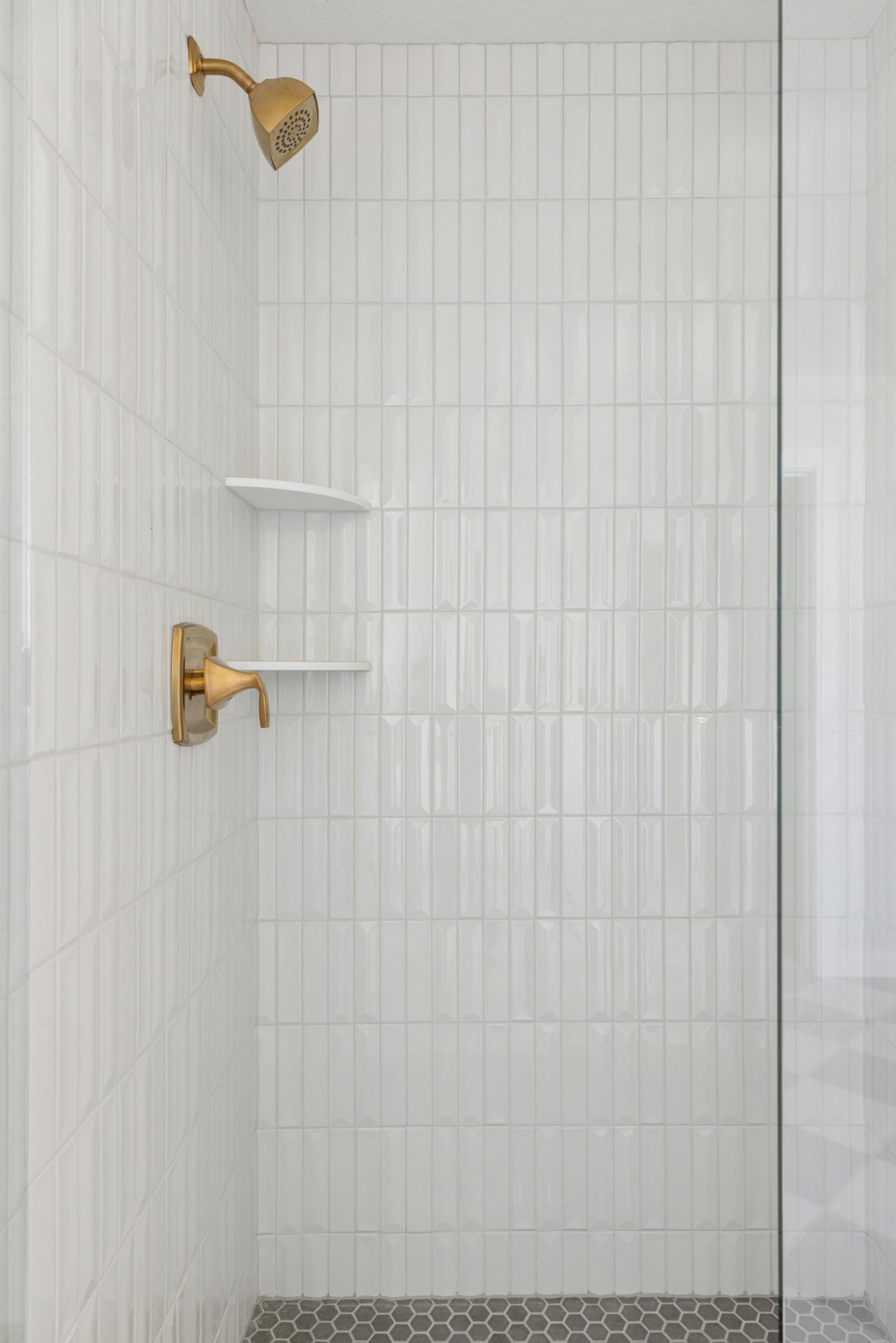 Primary bath shower features frameless shower door, tile walls and tile floor.
