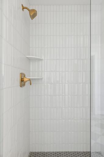 Primary bath shower features frameless shower door, tile walls and tile floor.