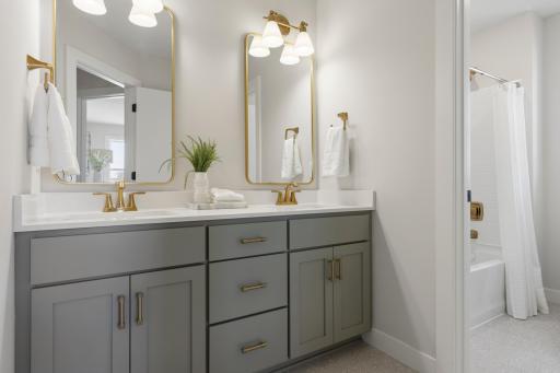 Double vanity with quartz countertops and separate room for tub.