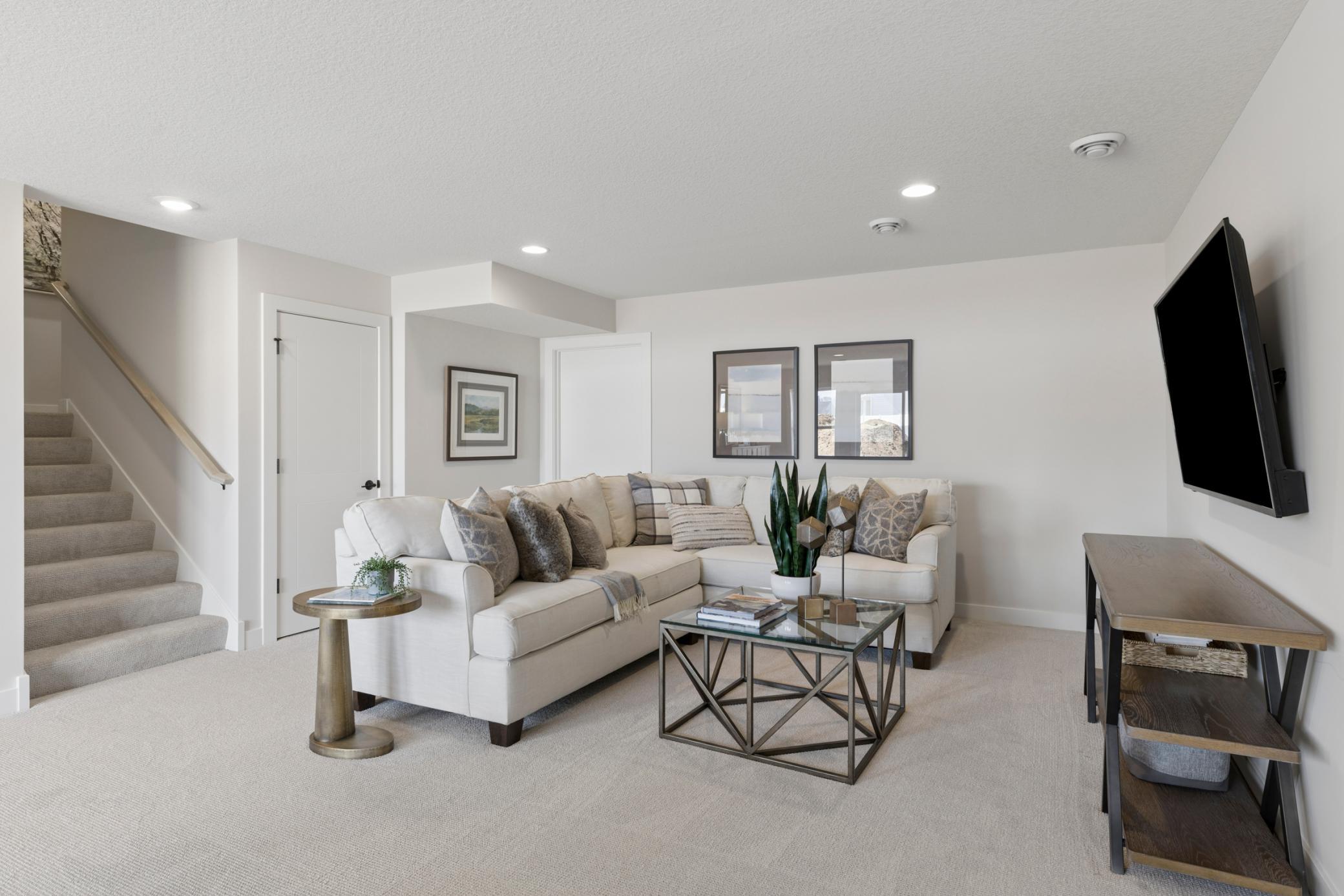 Lower level family room, located off wide stairway to main floor, is one of three family room spaces within home.