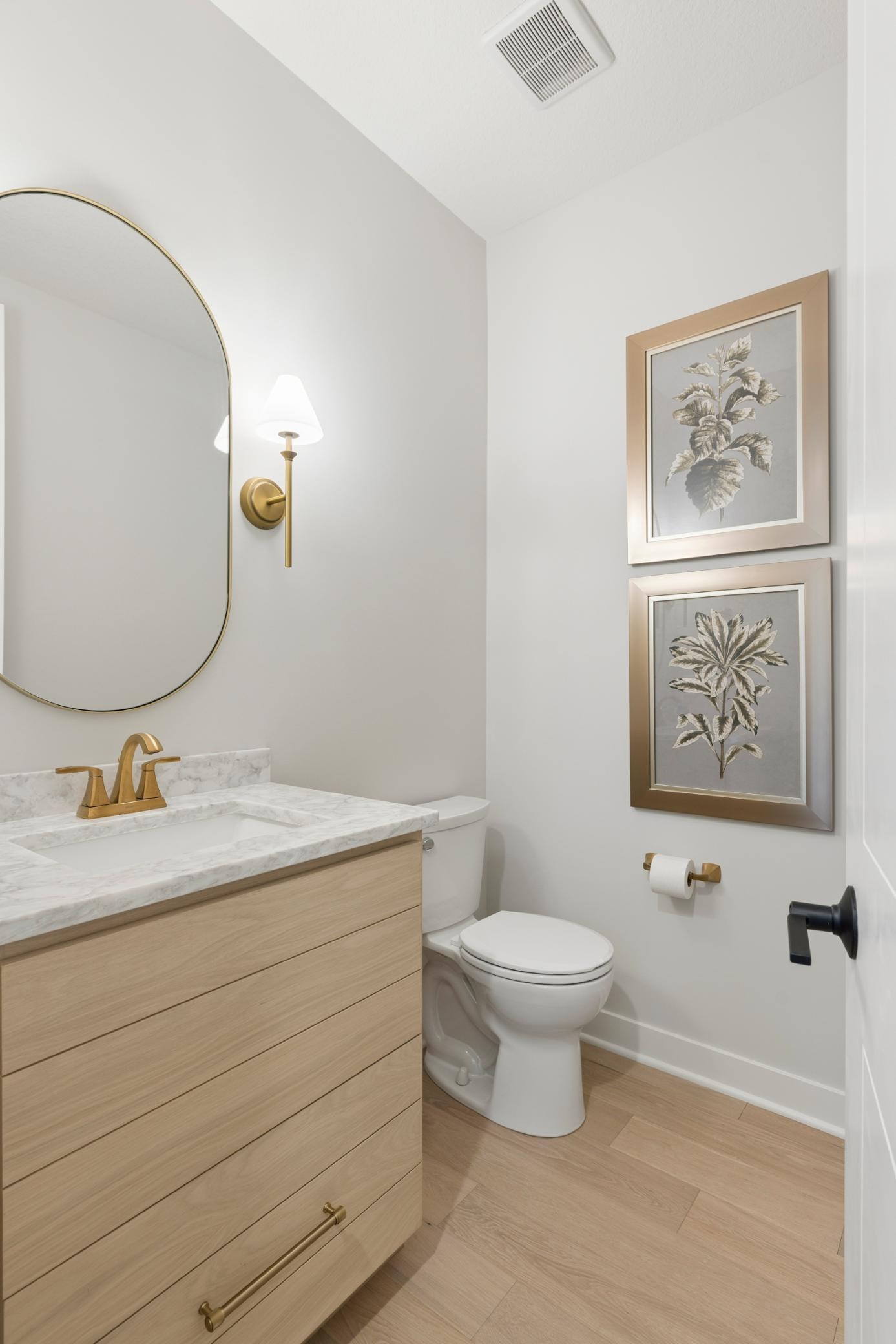 Powder room features custom white oak vanity with quartz countertops along with beautiful framed mirror.