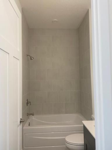 Main bath features a floor-to-ceiling tiled shower paired with a tub/shower comboâstyle and versatility in one space.