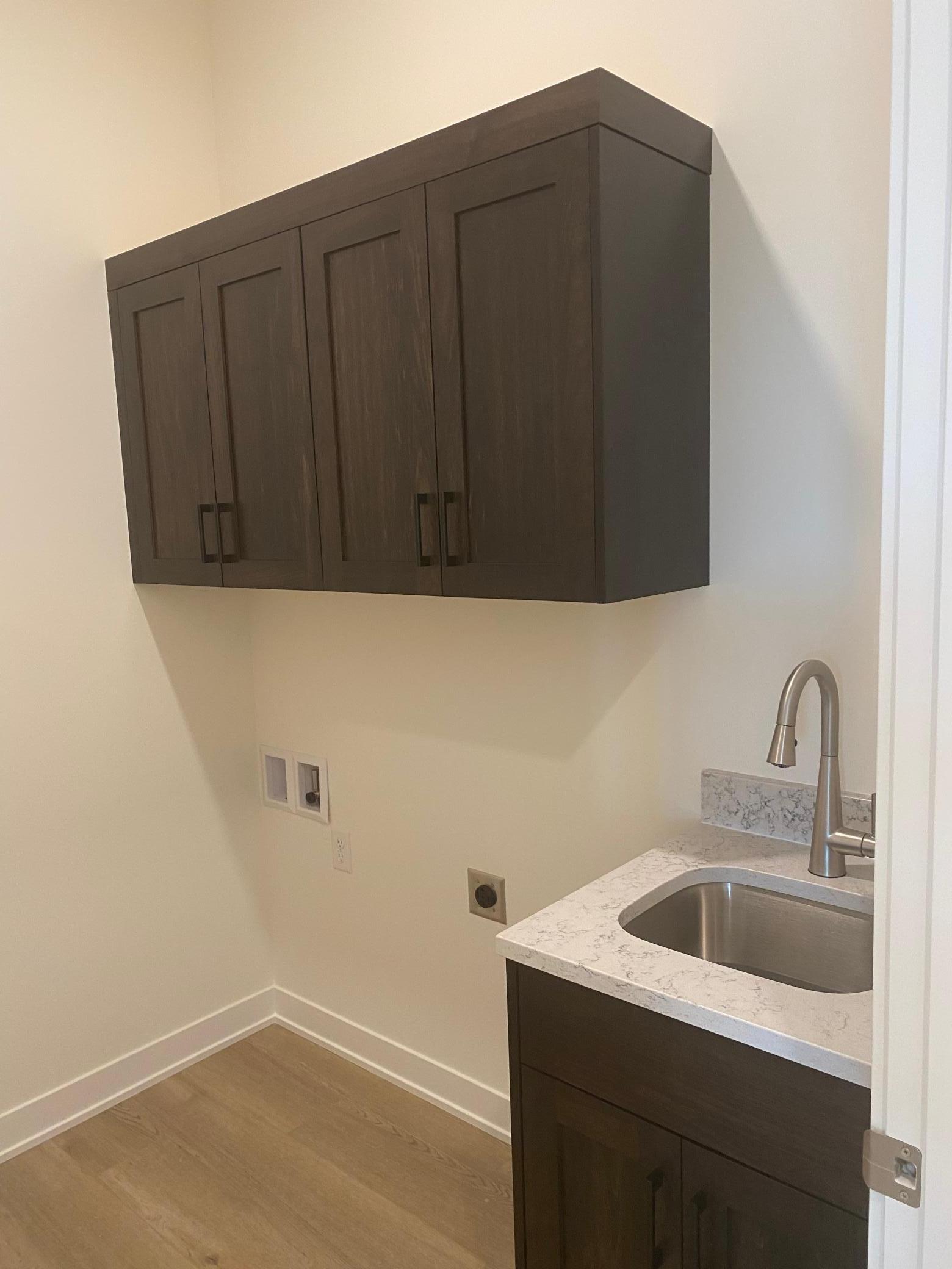 This home offers a functional laundry room located just off the mudroom, complete with a built-in sink and upper cabinets for ample storage. Designed for efficiency and organization, it provides a perfect space for laundry tasks & cleaning!