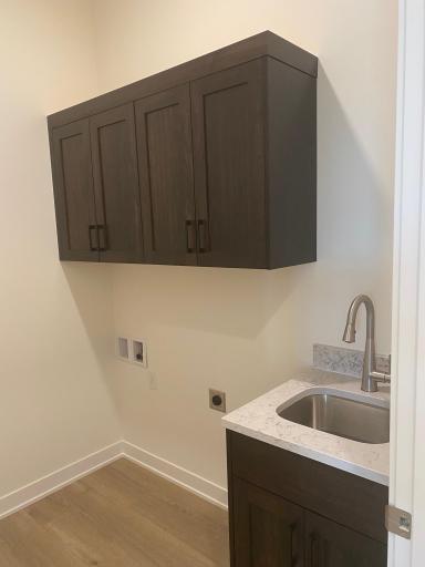 This home offers a functional laundry room located just off the mudroom, complete with a built-in sink and upper cabinets for ample storage. Designed for efficiency and organization, it provides a perfect space for laundry tasks & cleaning!