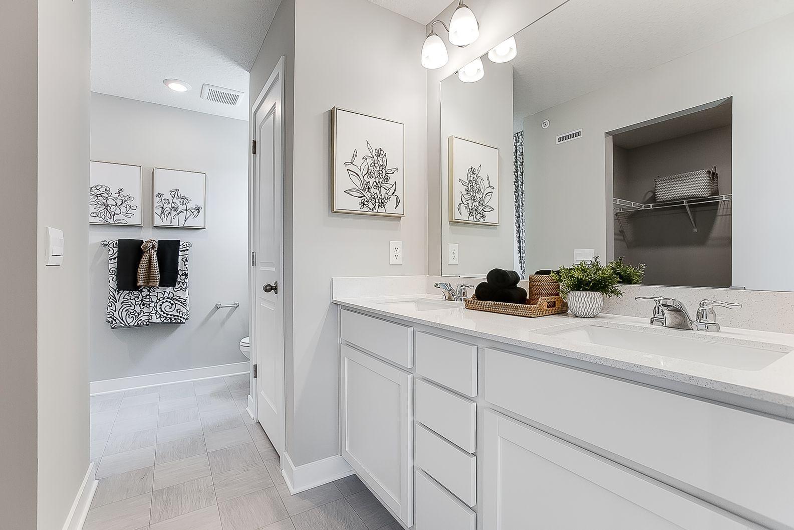 Primary bathroom offers a raised vanity with 2 sinks, Quartz counters and linen storage. *Model home, colors and finishes will vary.