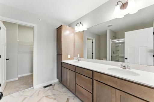 Owner's bath with dual vanity and large linen closet leading to 1 of 2 walk-in closets. Similar home shown, options can vary.