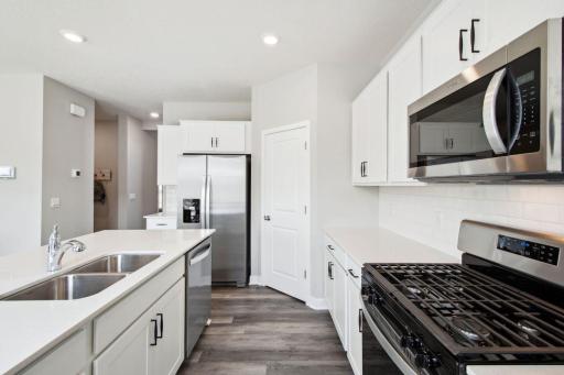 A stunning kitchen layout, all while remaining remarkably functional: The Quartz is endless, the sink is under-mount, the range is gas, micro-hood is vented to the exterior of the home-all soaked in light! Photo of model, colors & options will vary.