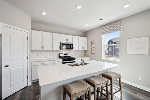 The heartbeat of the kitchen - this Island has loaded of counter space all coated in quartz counter-tops with an overhang large enough to fit a handful of bar stools! Photo of model, colors & options will vary.