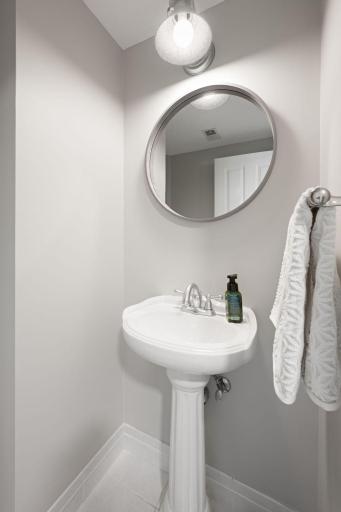 Convenient half bath with pedestal sink, updated mirror, wall sconce lighting, and clean neutral finishes.
