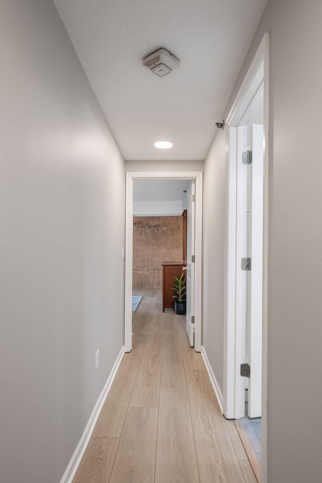 Clean interior hallway with updated flooring, neutral paint, recessed lighting, and easy access to the bedrooms and bath.