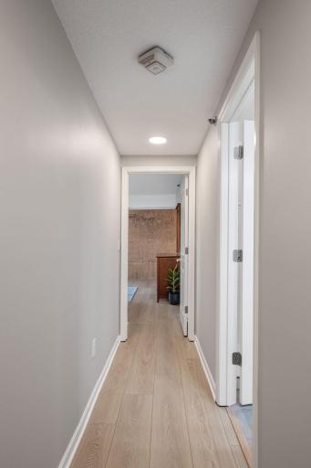 Clean interior hallway with updated flooring, neutral paint, recessed lighting, and easy access to the bedrooms and bath.