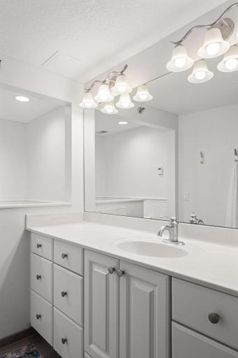 Bright bathroom vanity with generous counter space, ample cabinet storage, large mirror, and updated lighting.