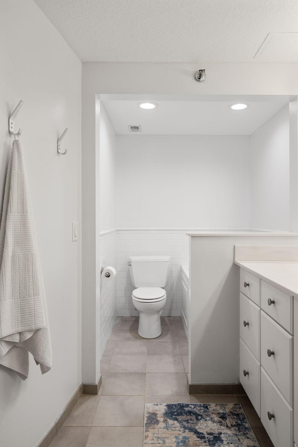 Tile flooring, subway tile surround, and convenient separation from the vanity space.