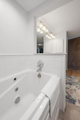 Relaxing soaking tub with white subway tile surround, neutral finishes, and easy access from the vanity area.