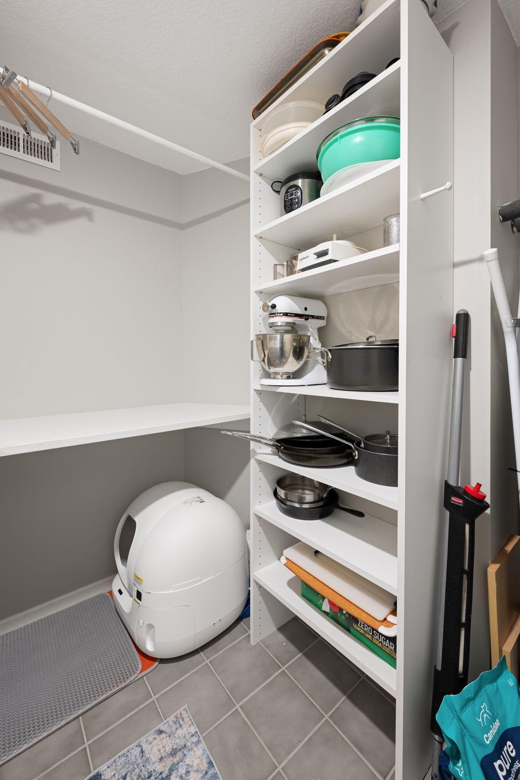 Large storage area with built-in shelving, tile flooring, and flexible space for household items, pantry overflow, or seasonal storage.