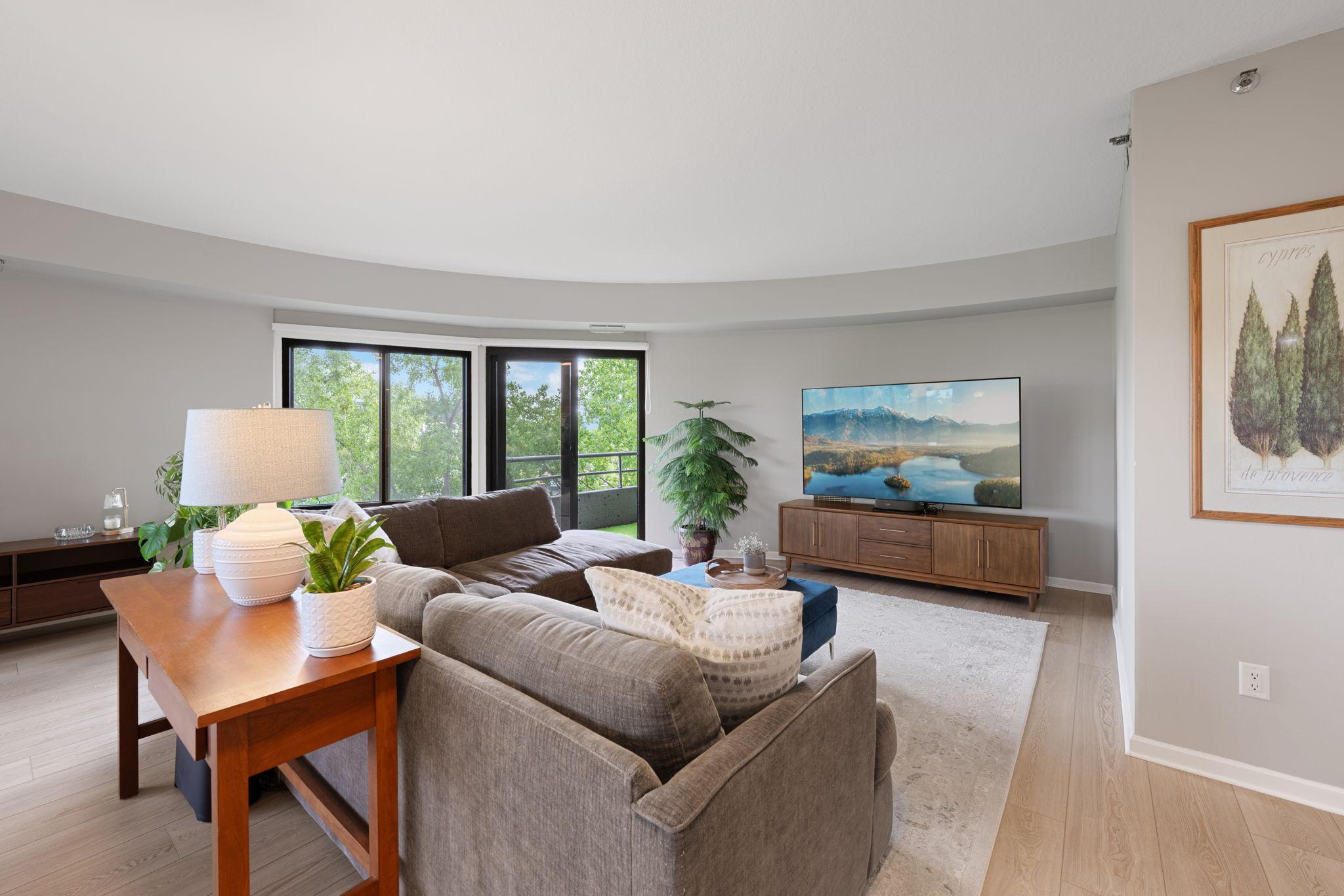 Spacious living room with expansive windows, beautiful natural light, stylish flooring, and a comfortable open layout.
