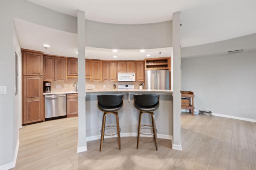 Open kitchen with breakfast bar seating, warm cabinetry, stainless steel appliances, and great connection to the living spaces.