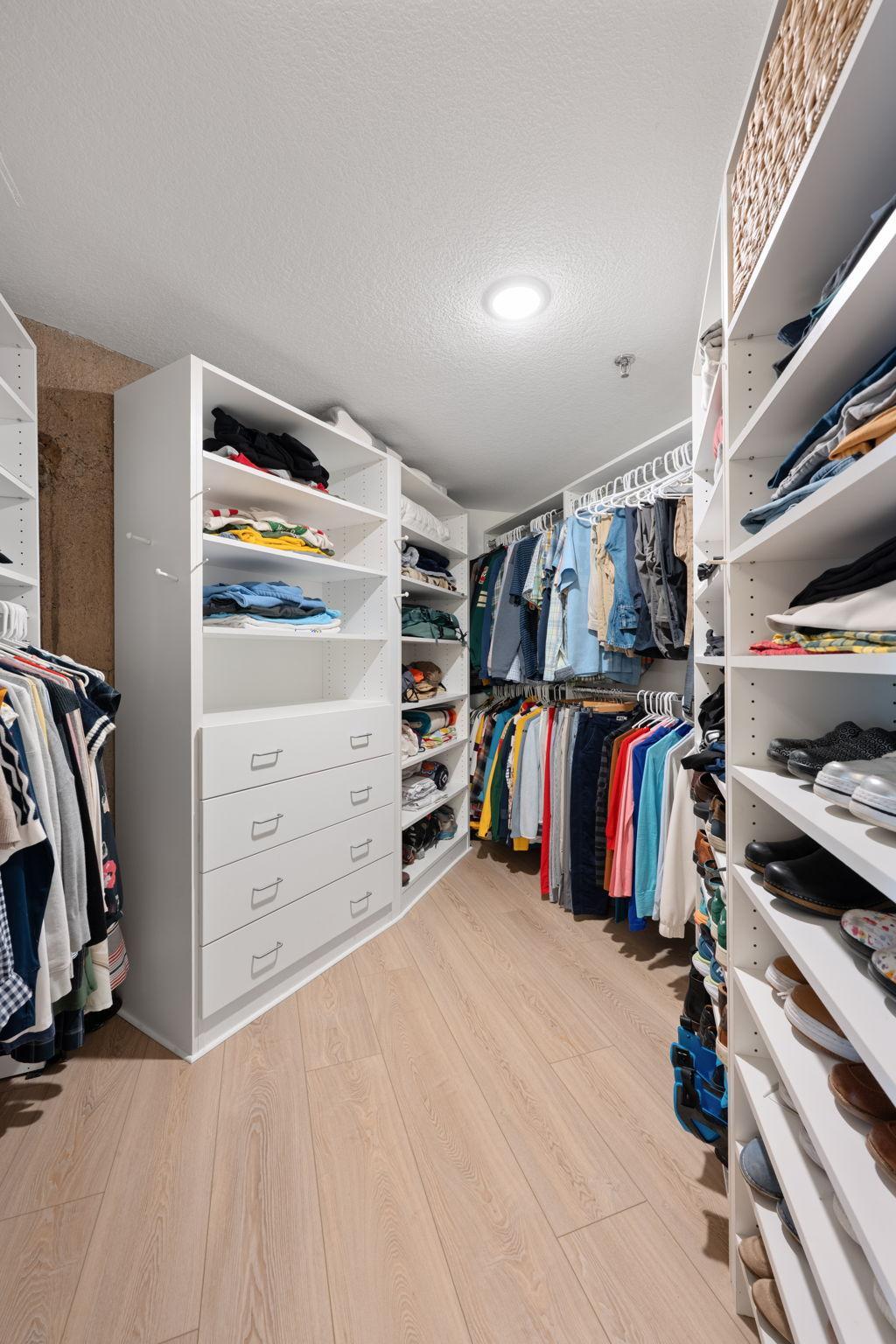 Oversized primary bedroom walk-in closet with custom built-in shelving, drawers, hanging space, and excellent organization throughout.