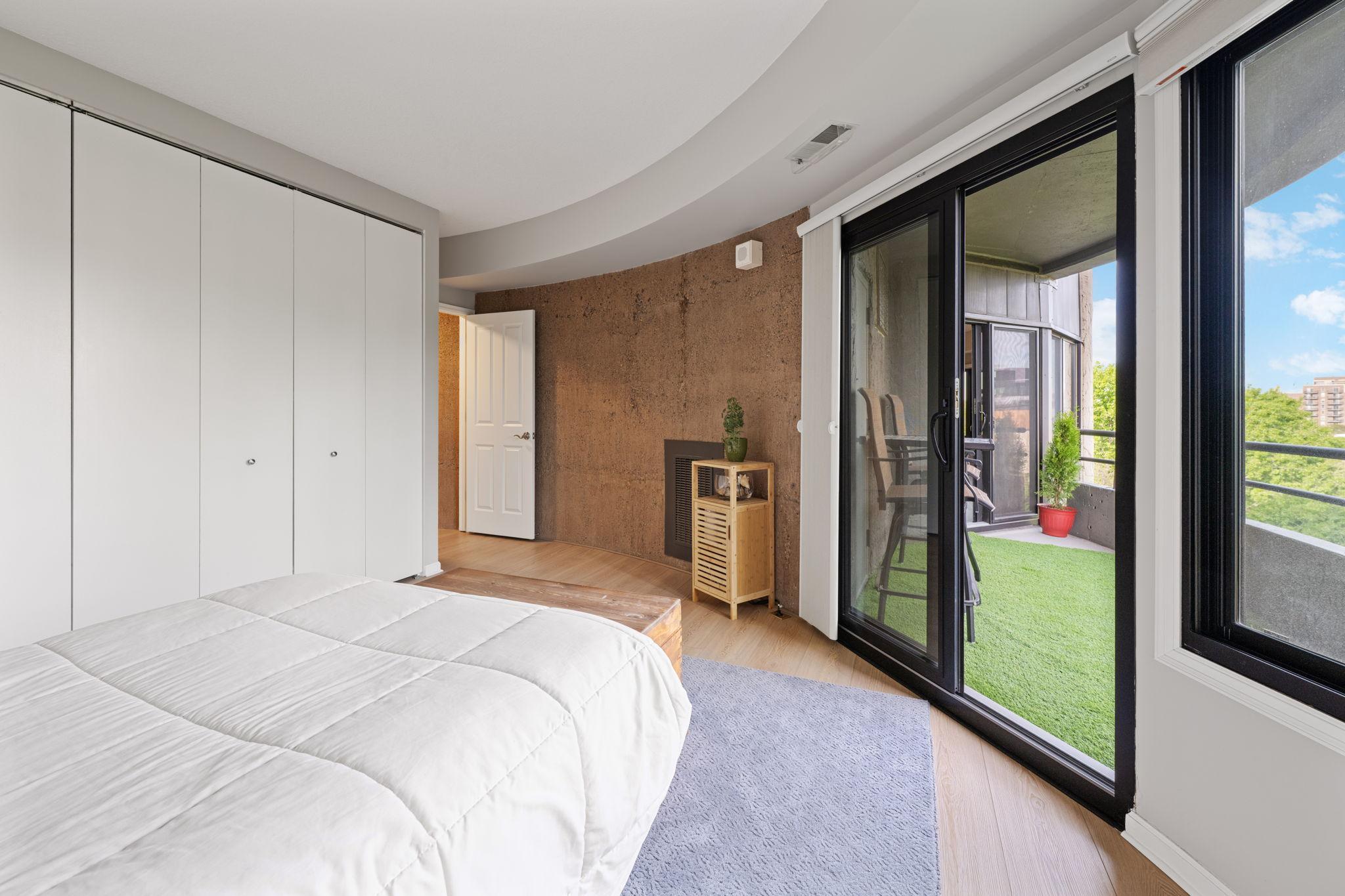 2nd Bedroom with sliding glass doors leading to the private balcony, plus oversized windows and a distinctive architectural accent wall.