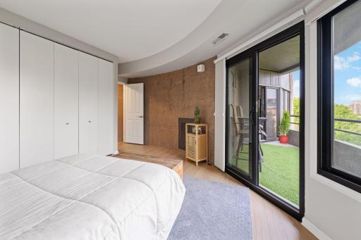 2nd Bedroom with sliding glass doors leading to the private balcony, plus oversized windows and a distinctive architectural accent wall.