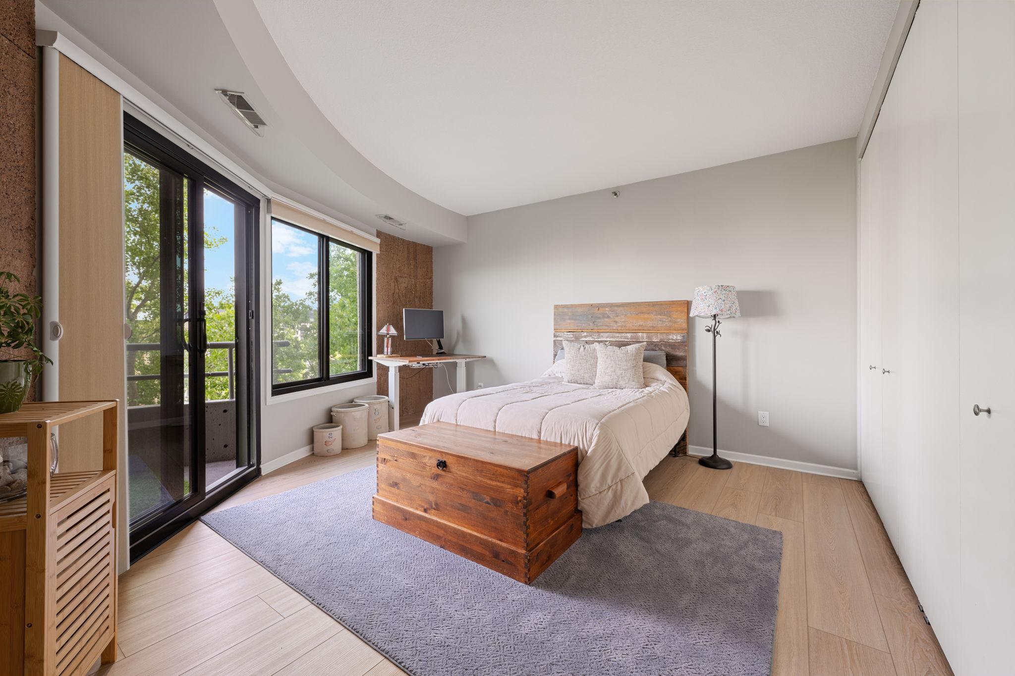 Spacious secondary bedroom with large windows, updated flooring, generous closet space, and direct access to the private balcony.