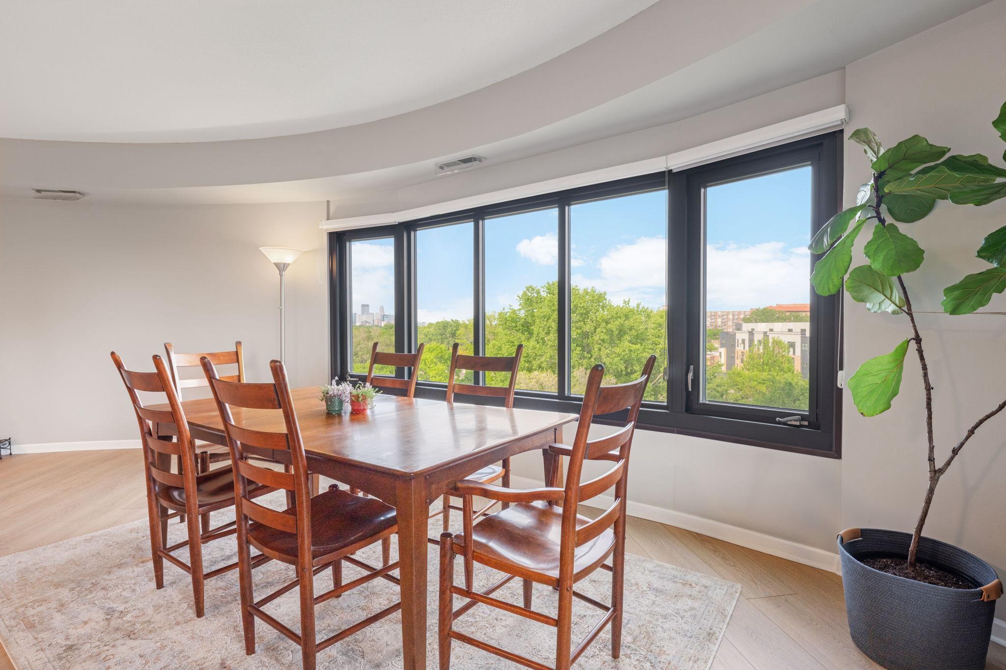 Bright dining space framed by oversized windows, offering beautiful treetop views and a glimpse of the Minneapolis skyline.