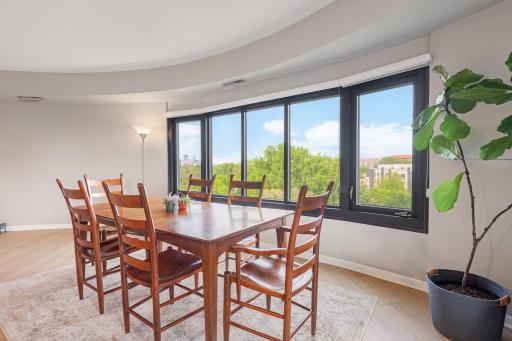 Bright dining space framed by oversized windows, offering beautiful treetop views and a glimpse of the Minneapolis skyline.