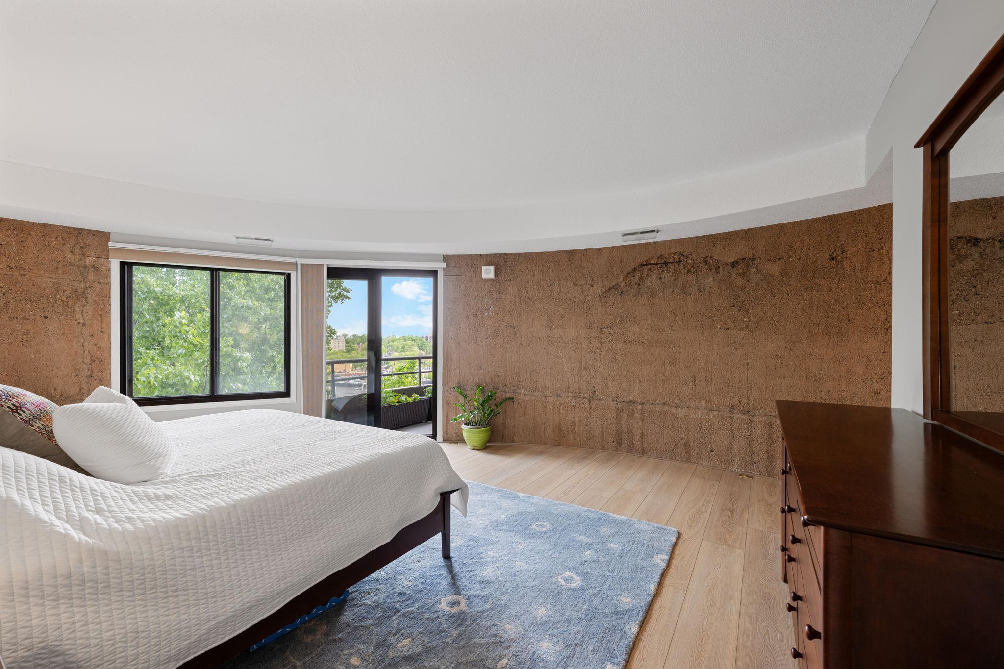 Generously sized primary bedroom with expansive wall space, large windows, updated flooring, and access to the private balcony.
