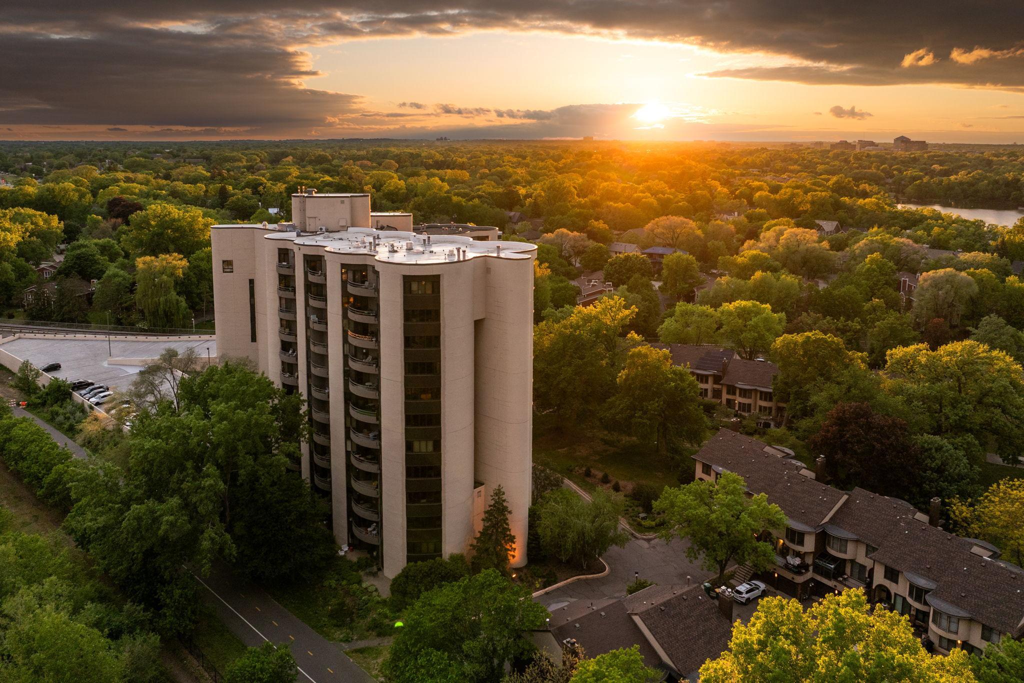 Stunning sunset aerial showcasing the building, surrounding treetops, nearby lakes, and peaceful Calhoun Isles scenery.