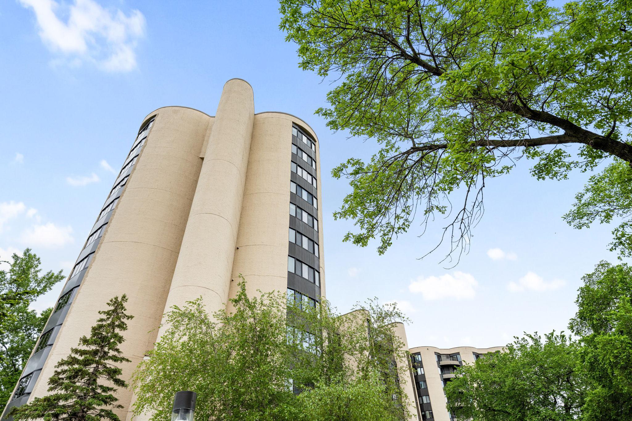 Iconic Calhoun Isles building exterior surrounded by mature trees, offering a distinctive architectural presence in a sought-after location.