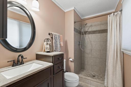 Private primary bathroom with a tiled walk-in shower, dark vanity, quartz countertop, and oil-rubbed bronze fixtures. Quietly elegant.