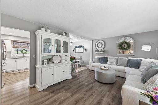 The spacious living room sits a half level above the entry, open to the kitchen and dining room â large windows, LVP flooring, and room for a generous sectional.