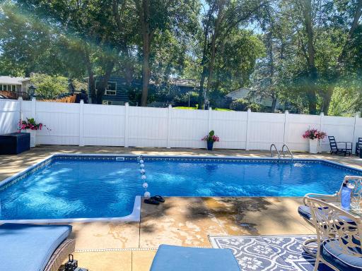 The 32x16 in-ground heated pool with stamped concrete surround â new pump in 2025, liner and heater less than 5 years old. White vinyl privacy fence encloses the entire yard.