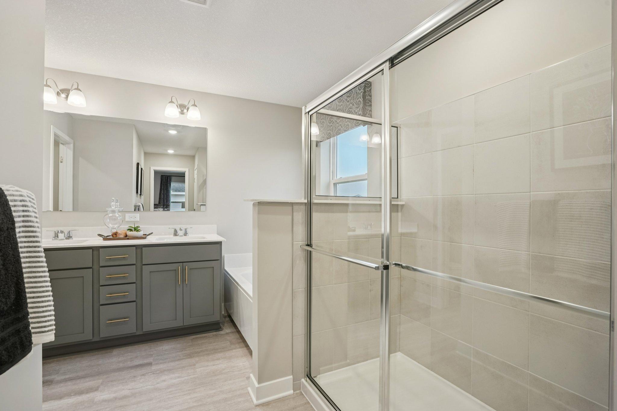 Your very own private bath featuring a tiled walk-in shower, soaking tub, and dual vanity with quartz countertops. (Photos of model. Colors and finishes may vary).