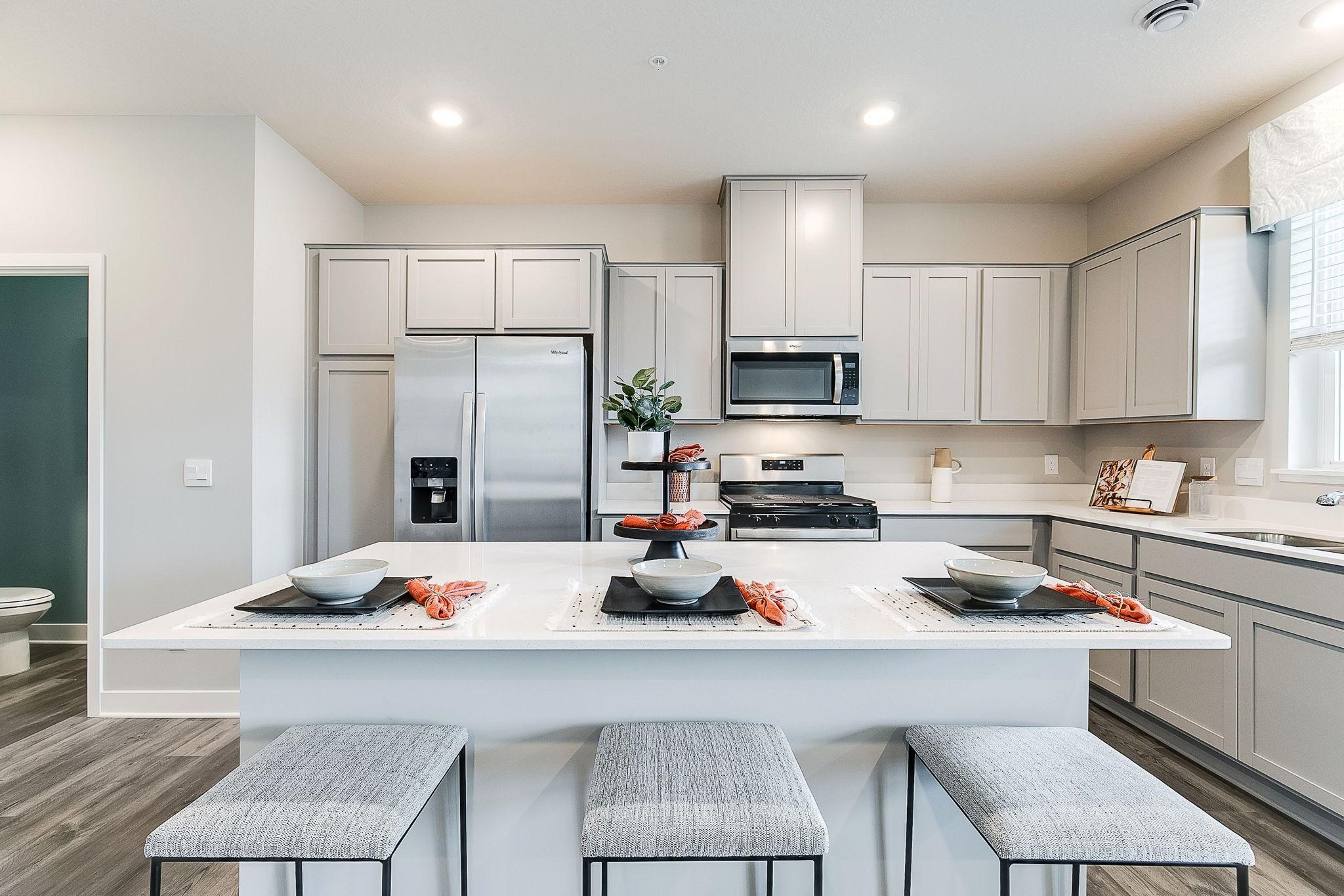 A kitchen built to both perform and enjoy - complete with a stainless appliance package, loads of cabinet space, quartz countertops, and an oversized center island. Model photos. Options and colors will vary.
