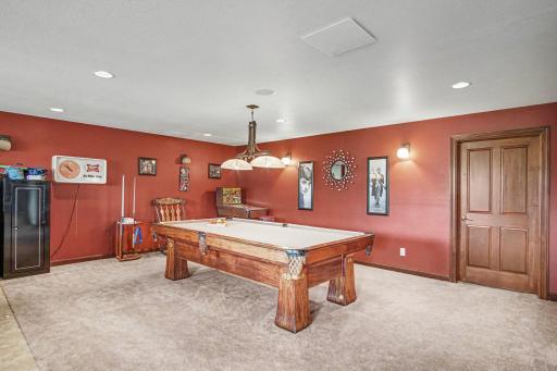 Carpeted rec room area, recessed lighting, with door to storeroom