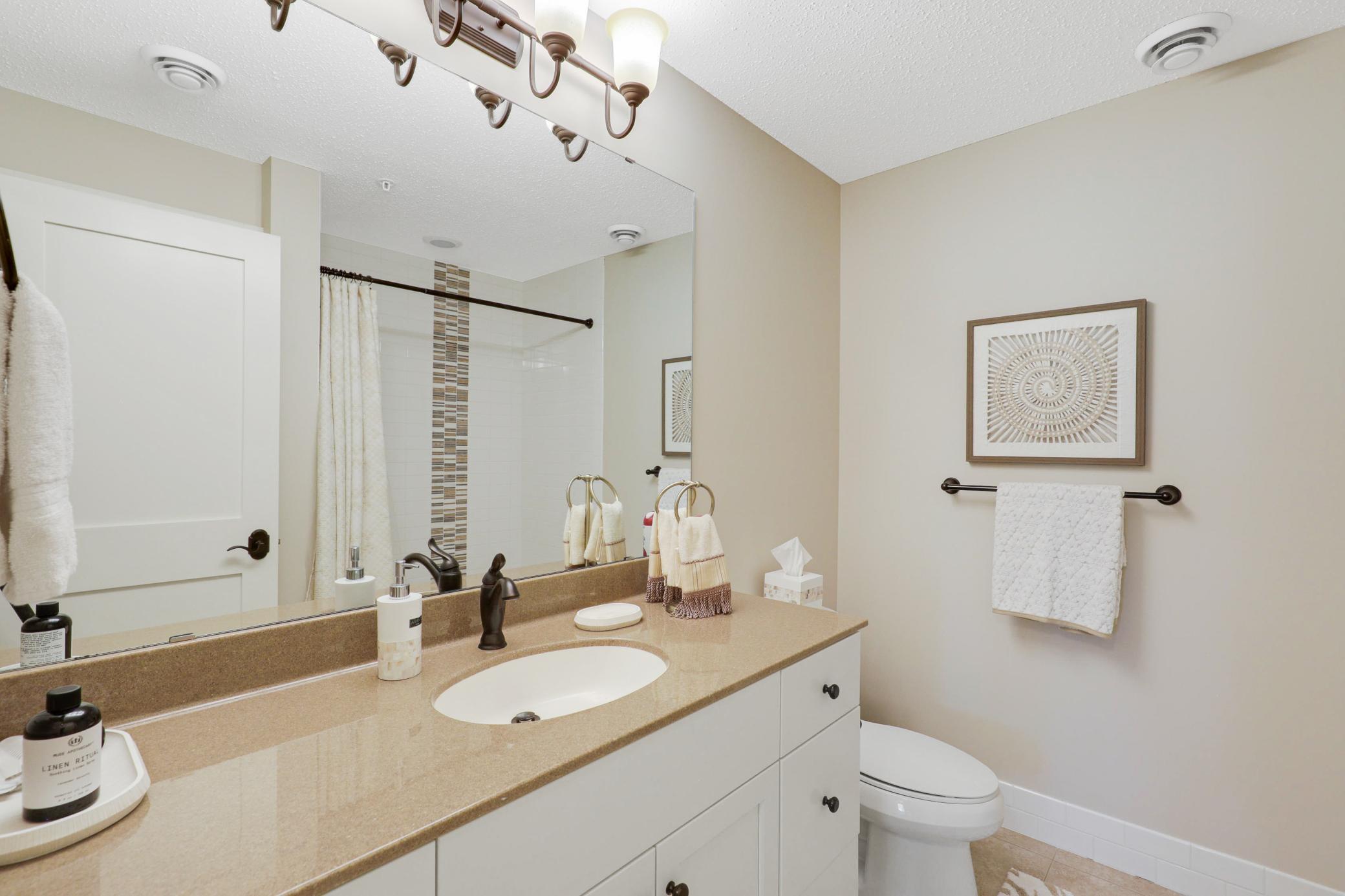 The lower level provides a generously sized third bedroom with a private full bath, dual closets, and direct access to the backyard, plus a utility room and dedicated storage space.