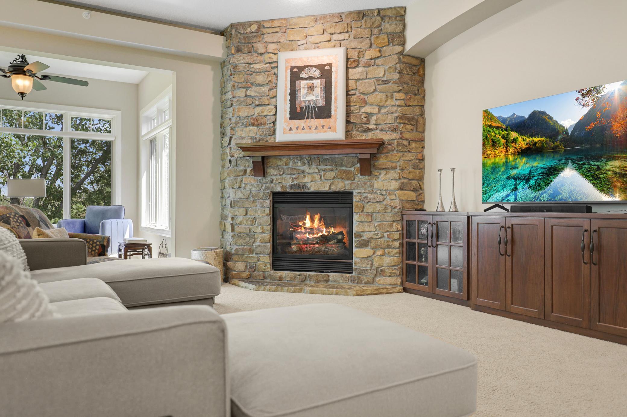 The bright living room is anchored by a gas fireplace with a stone surround and custom built-ins.
