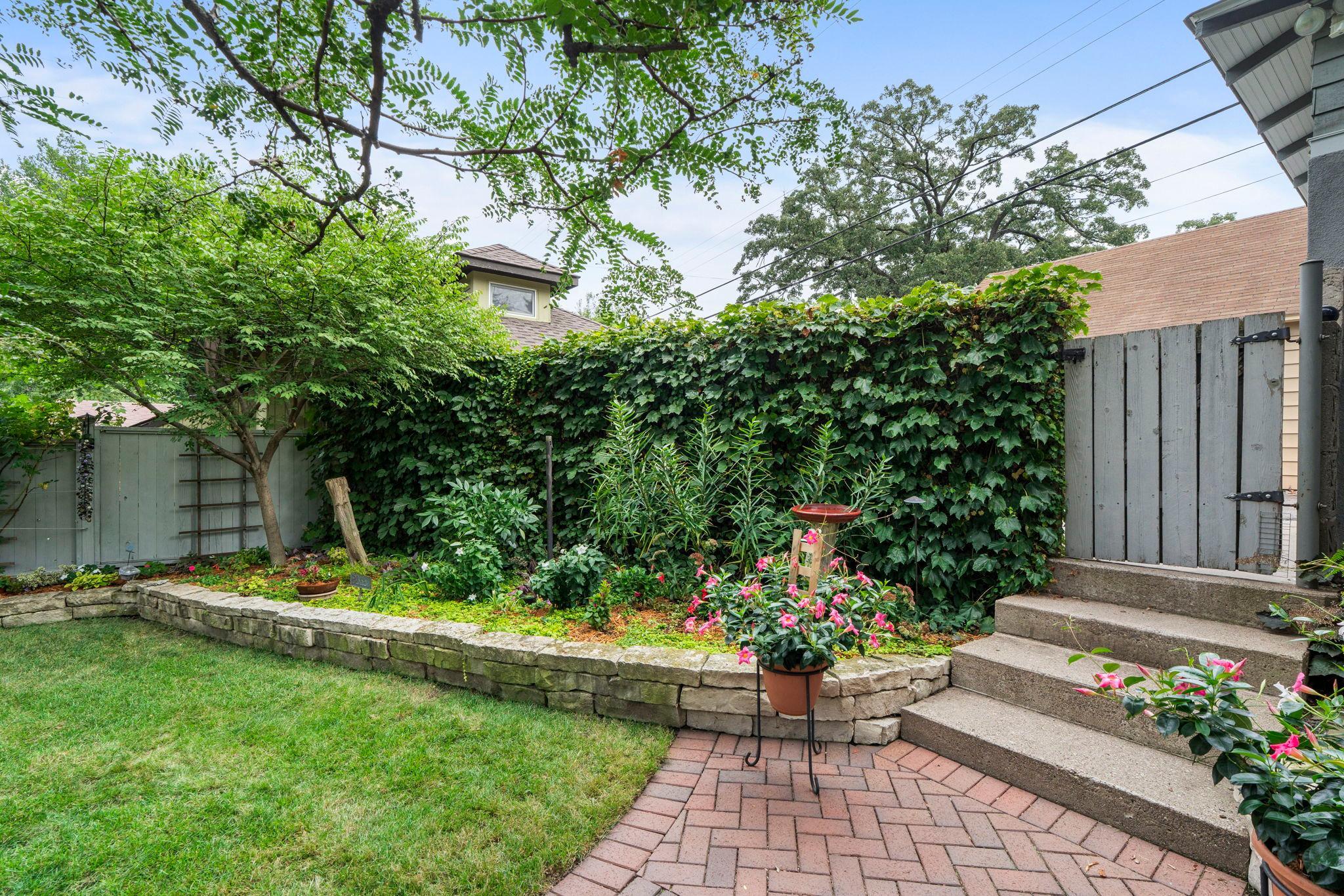 The gardens, stacked stone walls, clay brick paver walkway and patio make this backyard a very special place.