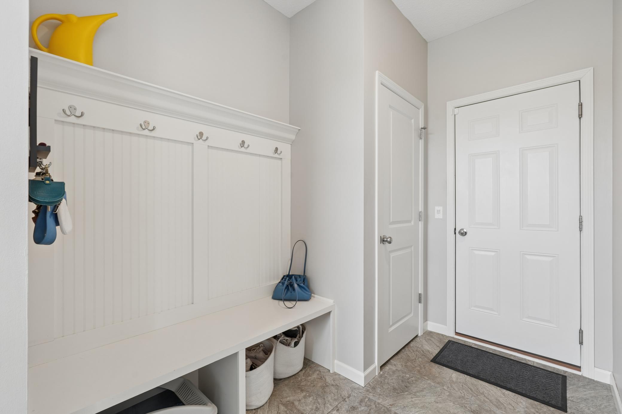 Cute mudroom area with built in bench and hooks