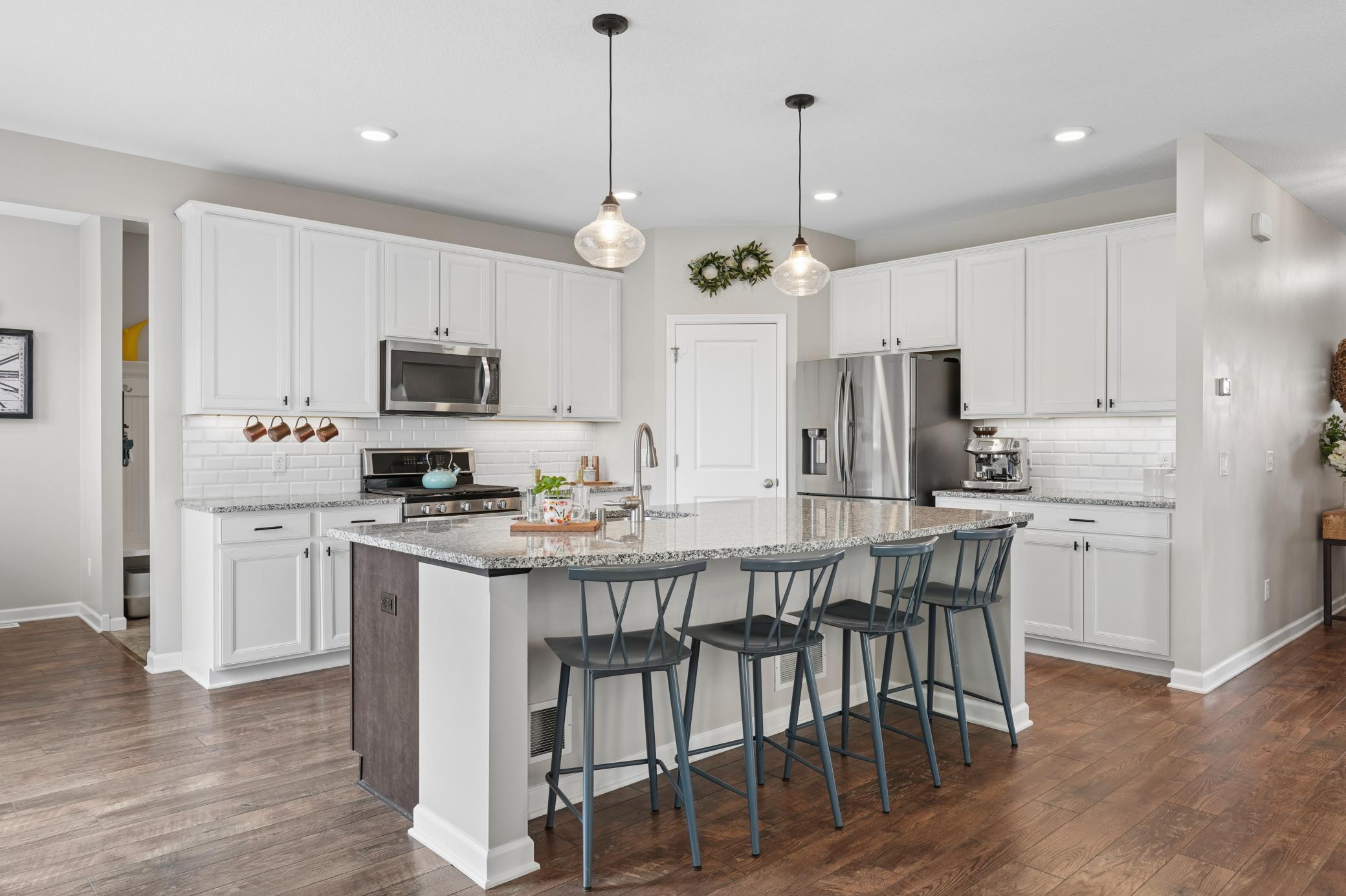 Kitchen with white maple cabinets, granite countertops, stainless steel appliances, walk-in pantry, and a large center island with breakfast bar seating