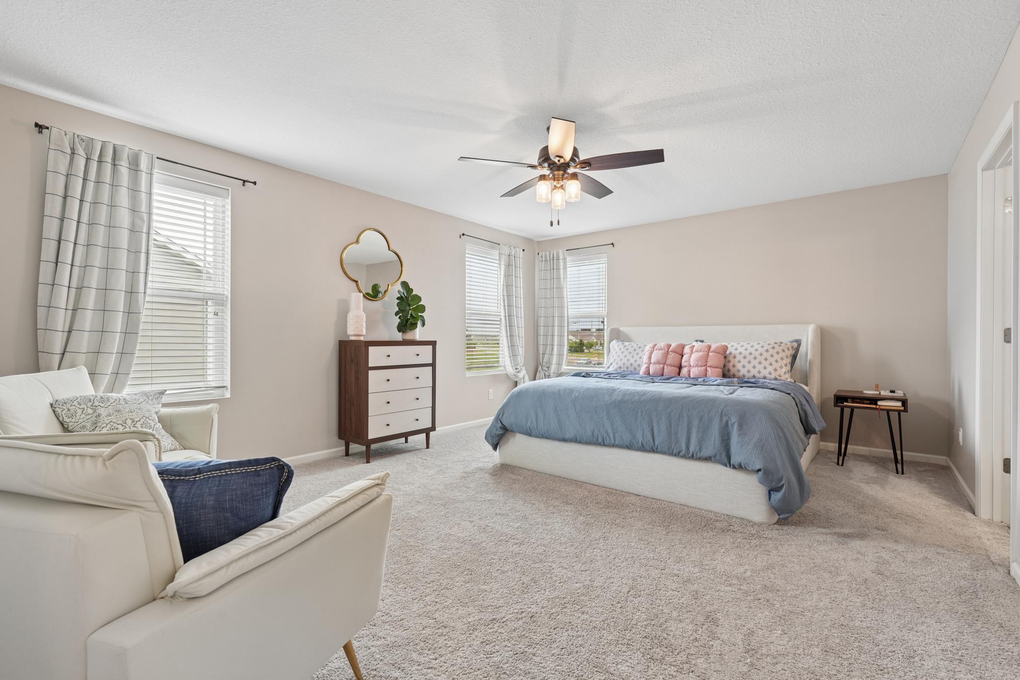 Private primary bedroom with ceiling fan and sitting area