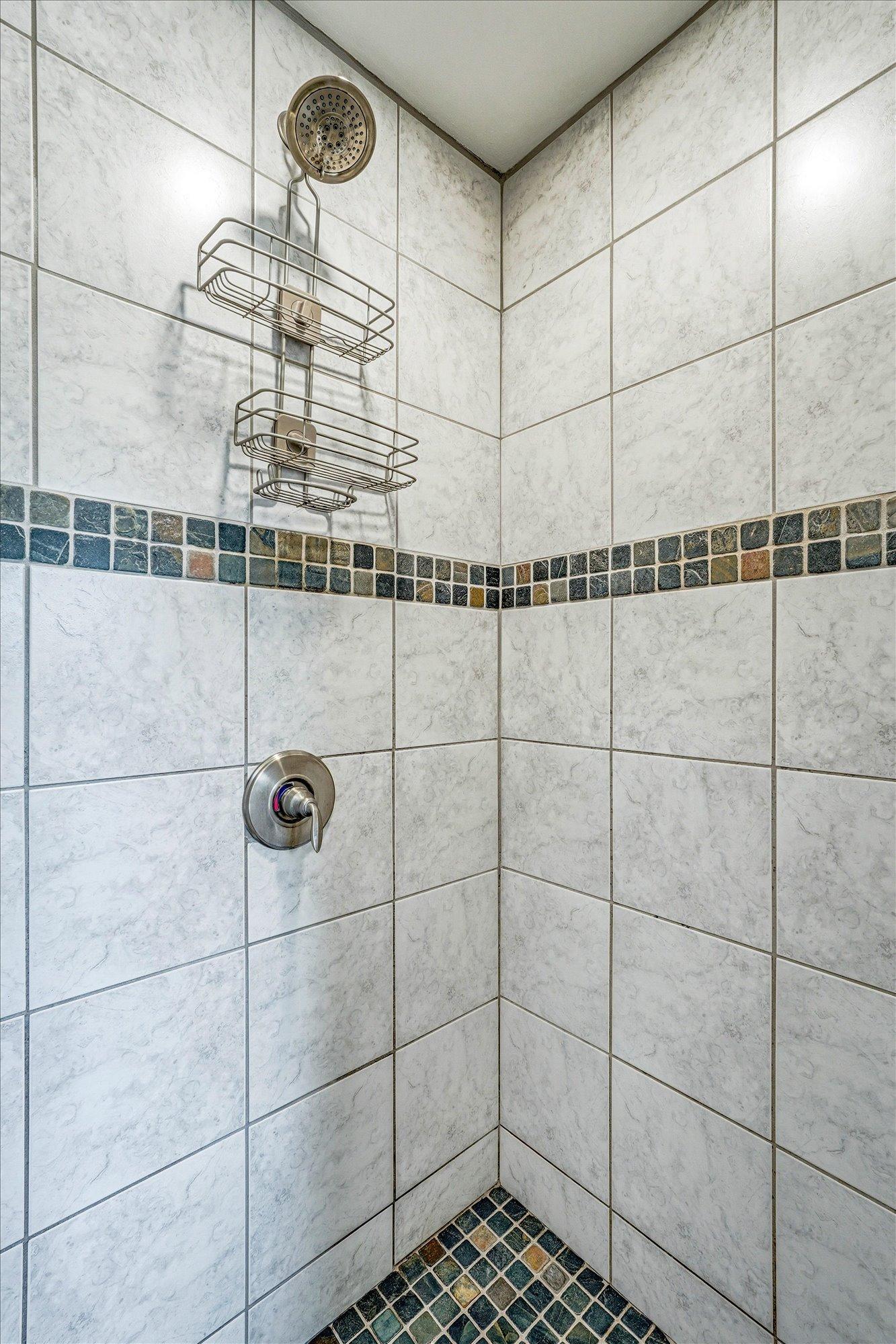Fully tiled shower-primary bathroom.