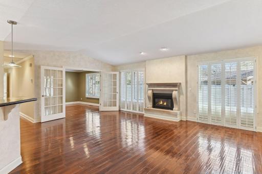 The vaulted living room has a gas log fireplace and opens to the dining room, kitchen and den.
