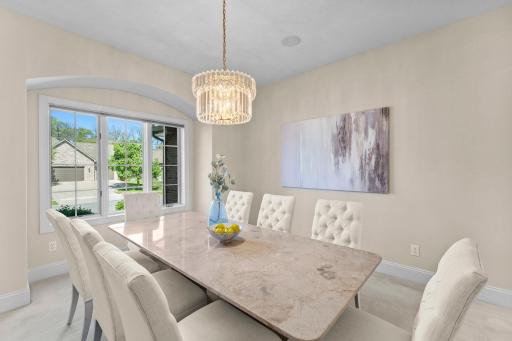 For more formal gatherings, the front-facing formal dining room offers cozy carpeting, a bay window, and a chandelier that creates an elegant setting, with the beautiful stone table included in the sale.