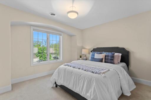 The fourth bedroom located on the upper level that features a large front-facing window.
