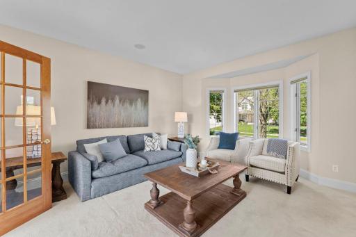 The main-level living room, also featuring a bay window and soft carpeting, is accessible from the foyer.