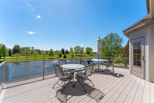 The spacious glass-railed deck overlooks serene water and golf course views.