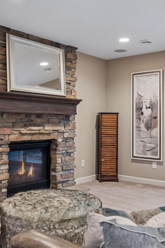 Lower-level gas fireplace with stone surround. (Fire has been virtually added to fireplace.)