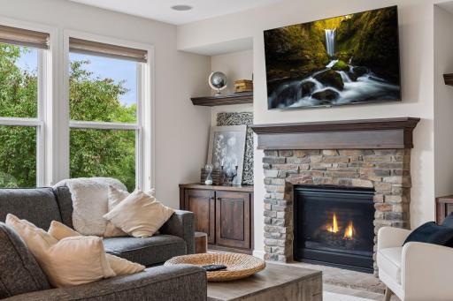 Family room is anchored by a gas fireplace with a stone-surround. (Fire has been virtually added to the fireplace)